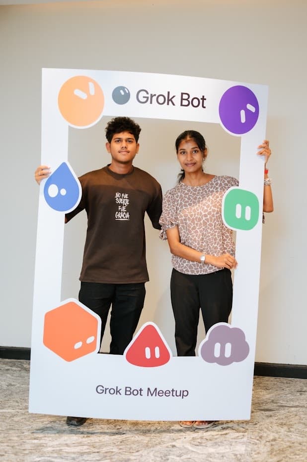 Two attendees posing in the Grok Bot Meetup photo frame