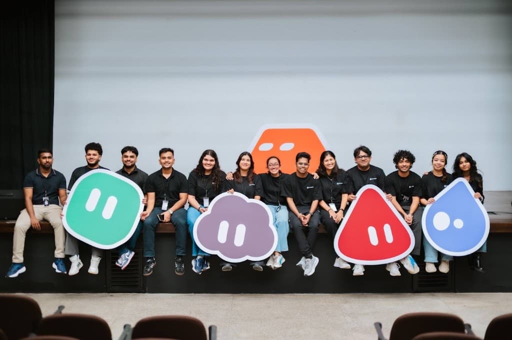 The Grok Bot Meetup Colombo crew sitting on the DHPL Auditorium stage holding giant Grok Bot character cutouts