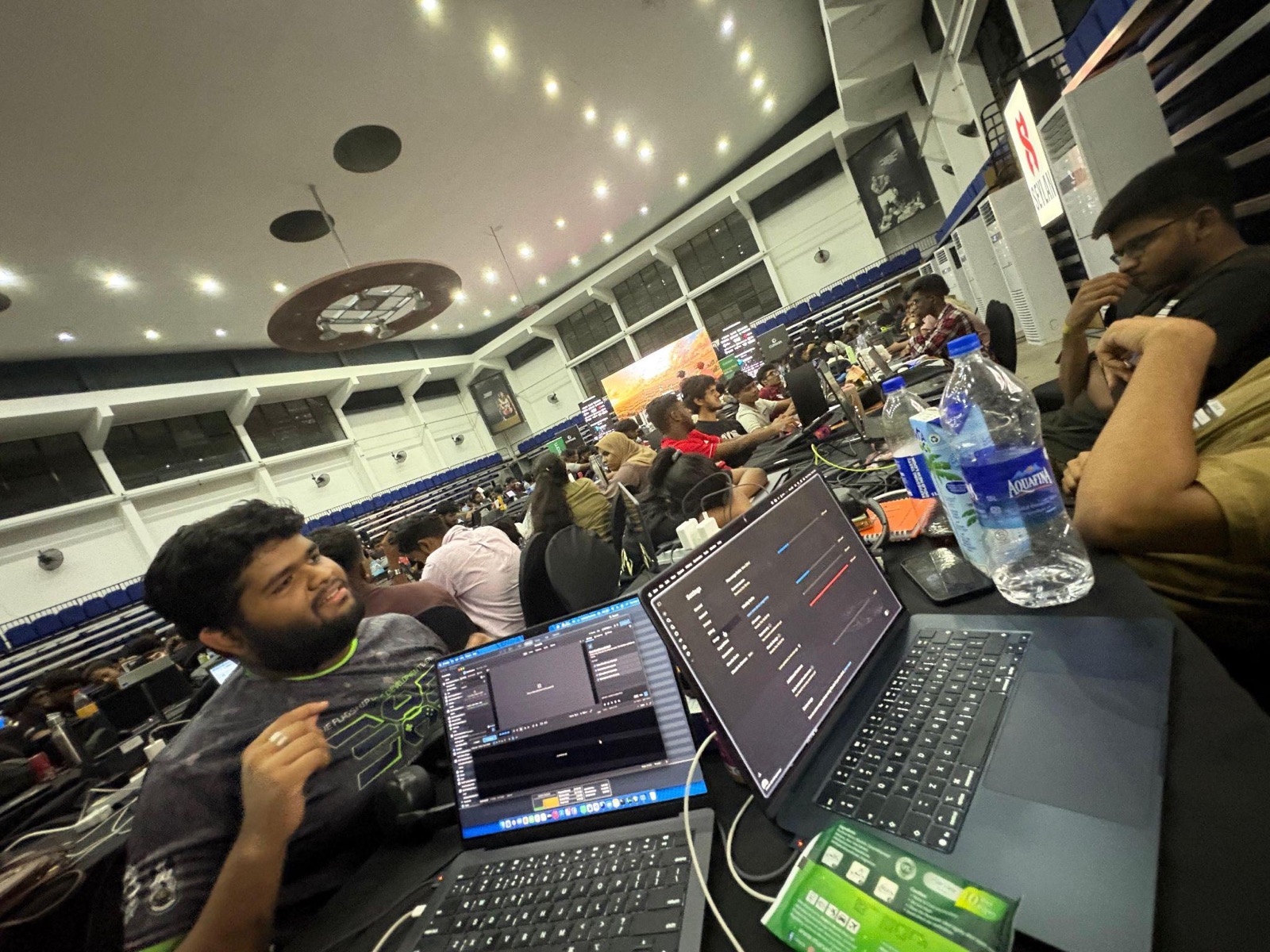 Two laptops at the BitByBit table: FrameOS on one screen and pipeline progress bars on the other